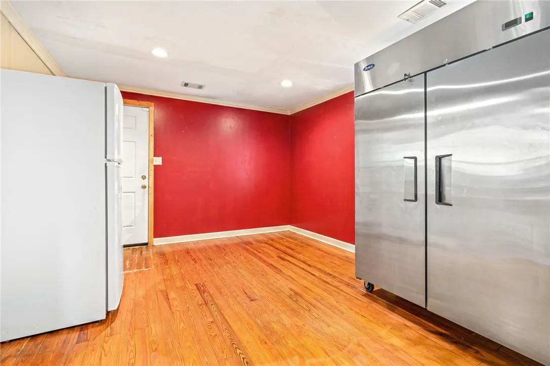 Hardwood floors and vivid red walls define this versatile room, featuring commercial-grade refrigeration units.