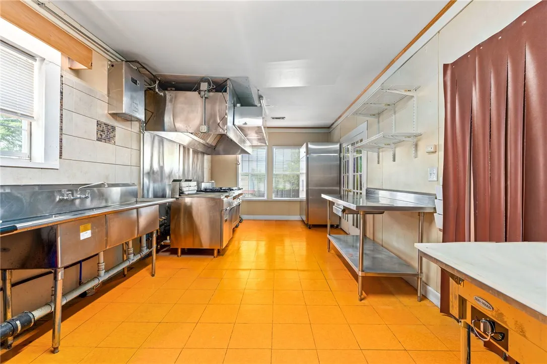 A vibrant yellow floor complements the professional-grade stainless steel appliances and ample workspace in this commercial kitchen.