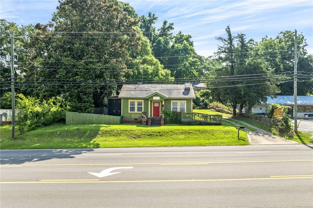 A charming single-story residence with a vibrant red door, nestled amidst lush greenery.