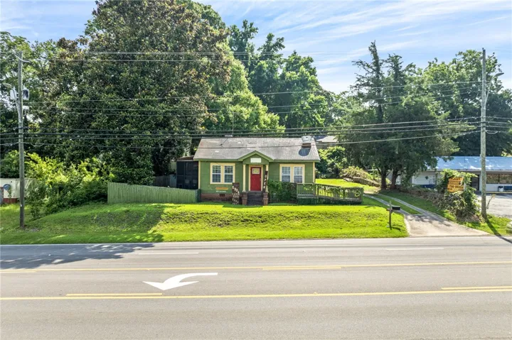 A charming single-story residence with a vibrant red door, nestled amidst lush greenery.