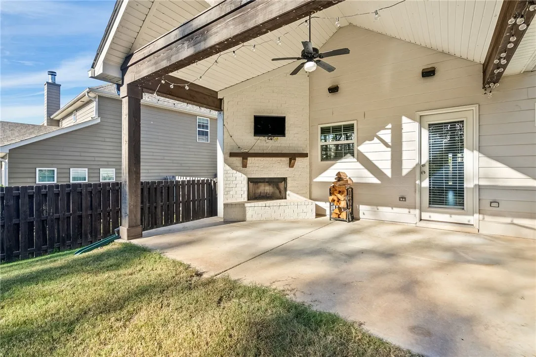 A spacious covered patio features a ceiling fan and a brick fireplace, ideal for outdoor gatherings.