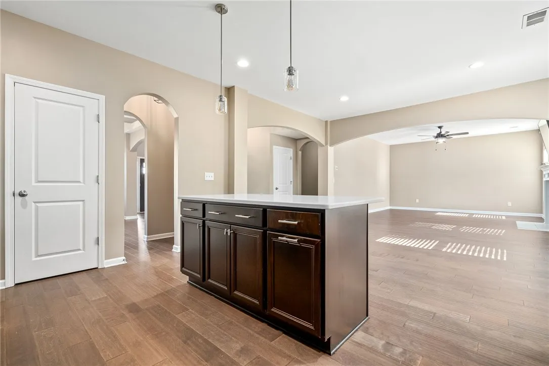A central kitchen island defines the open floorplan connecting to an expansive living area with rich hardwood flooring.