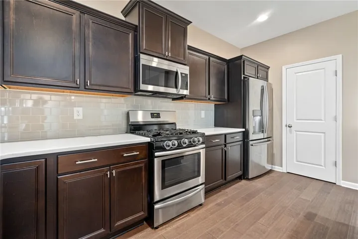 Culinary aspirations come alive in this kitchen featuring dark cabinetry and lustrous countertops.