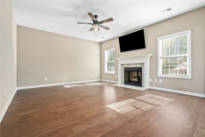 A well-lit living area features warm wood flooring and a classic fireplace as its focal point.