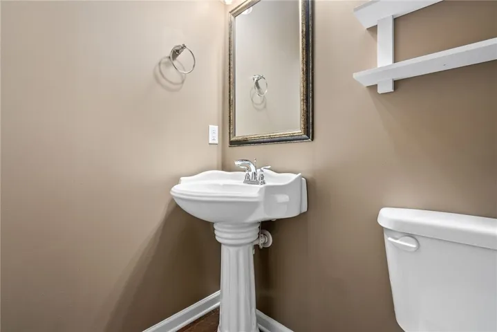 A compact and functional powder room with a classic pedestal sink and ample wall space.