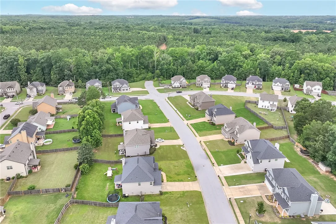 An aerial perspective reveals a harmonious suburban development nestled against a verdant forest backdrop.