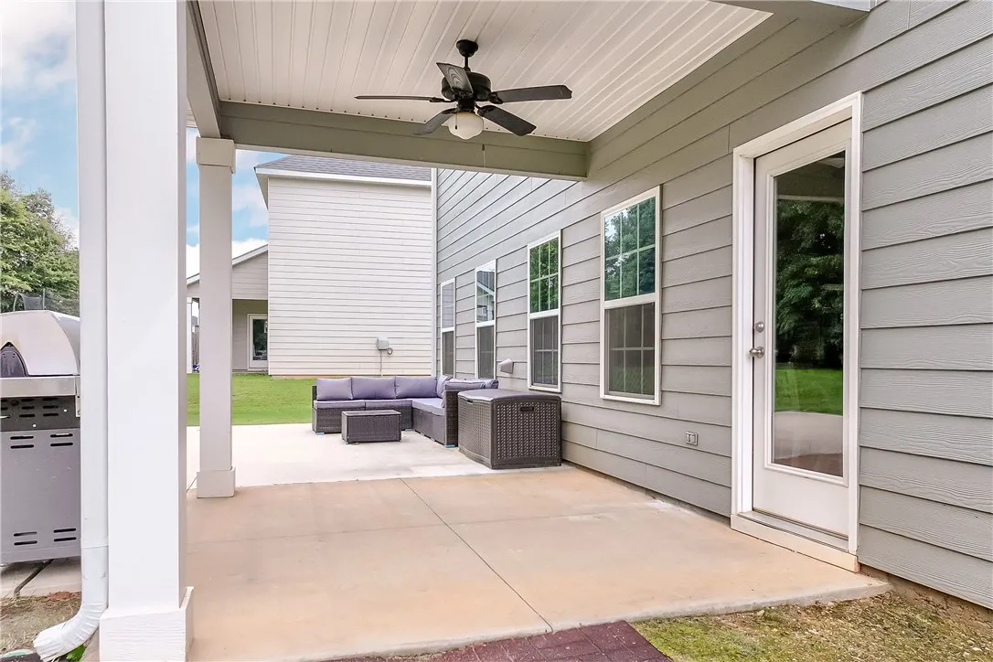 An inviting covered patio with a ceiling fan, offering a pleasant outdoor living area perfect for relaxation.