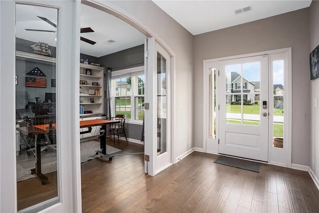 A welcoming entry offers rich wood flooring and a direct view into a versatile home office.