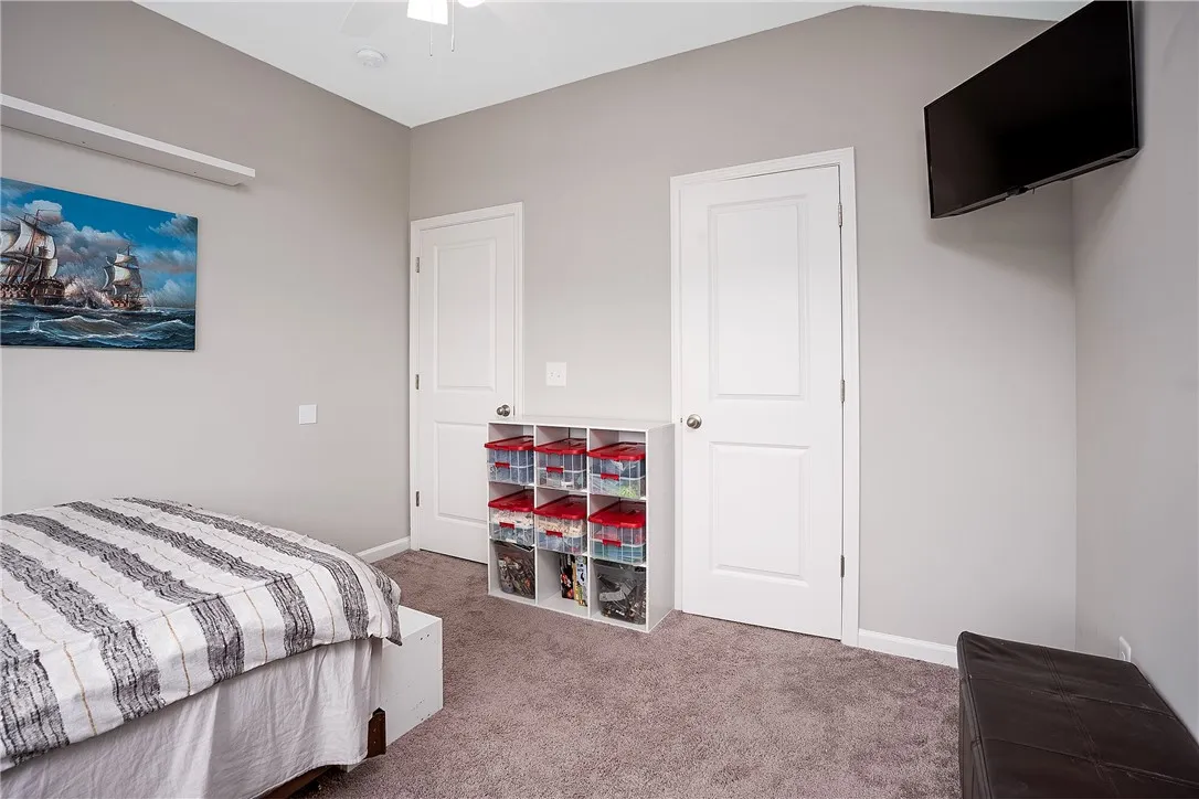 Comfortable bedroom features carpeted floors and a practical ceiling fan.