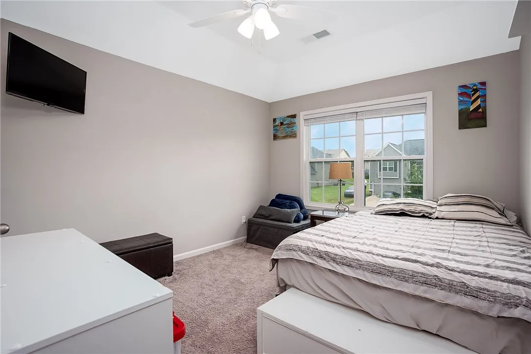A comforting bedroom with soaring vaulted ceilings and a broad window offers a neighborhood vista.