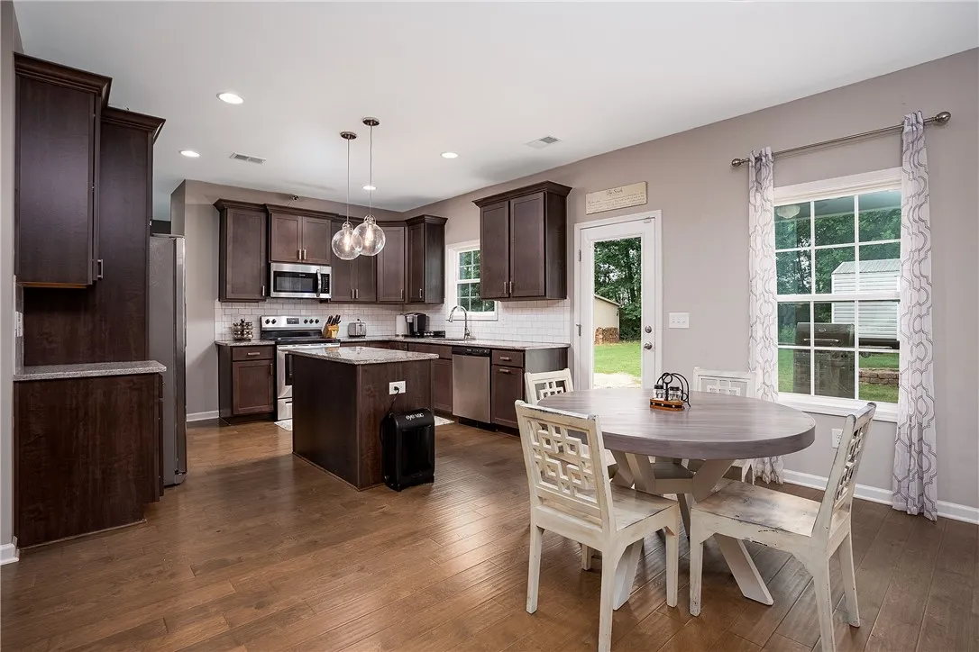 An open-concept kitchen and dining area features rich wood flooring and a convenient island with seating.