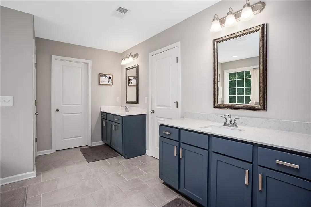 Dual vanities with sleek blue cabinetry and ample counter space define this functional bathroom.