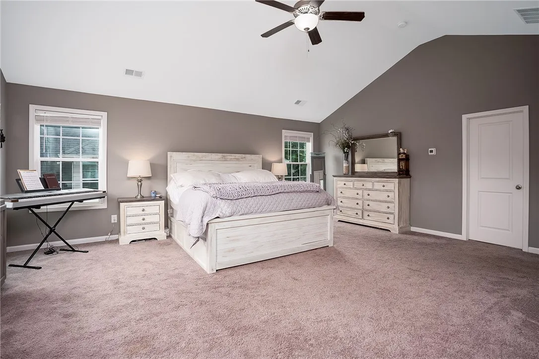 Sloped ceilings and a ceiling fan enhance the spacious feel of this well-lit primary bedroom.