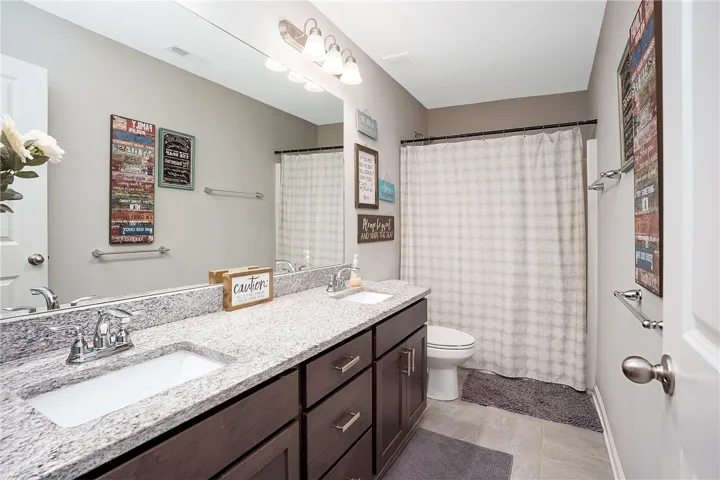 Double vanity with stone countertops and ample storage creates a practical and appealing bathroom space.