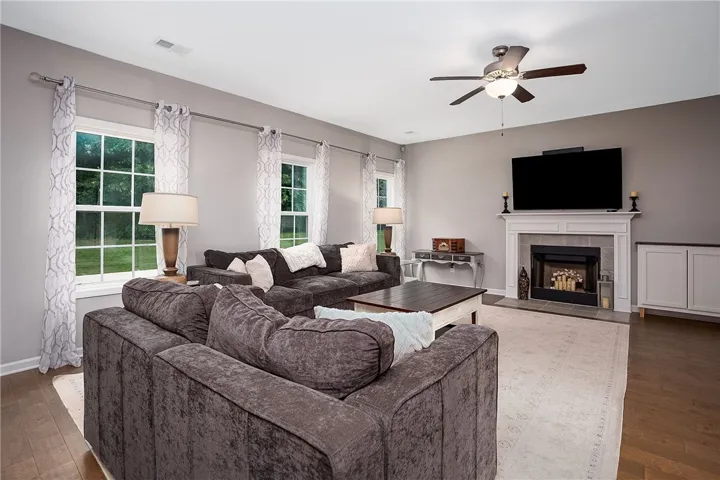 Natural light streams through multiple windows, illuminating the spacious living area with warm hardwood flooring.