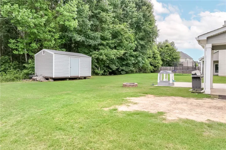 A spacious backyard retreat features a durable storage shed, fire pit, and ample room for outdoor activities.