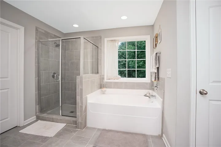 Indulge in this well-appointed bath, featuring a generous soaking tub and a sleek glass-enclosed shower.