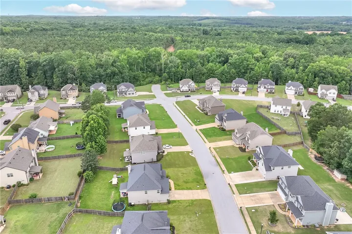 An aerial perspective reveals a harmonious suburban development nestled against a verdant forest backdrop.