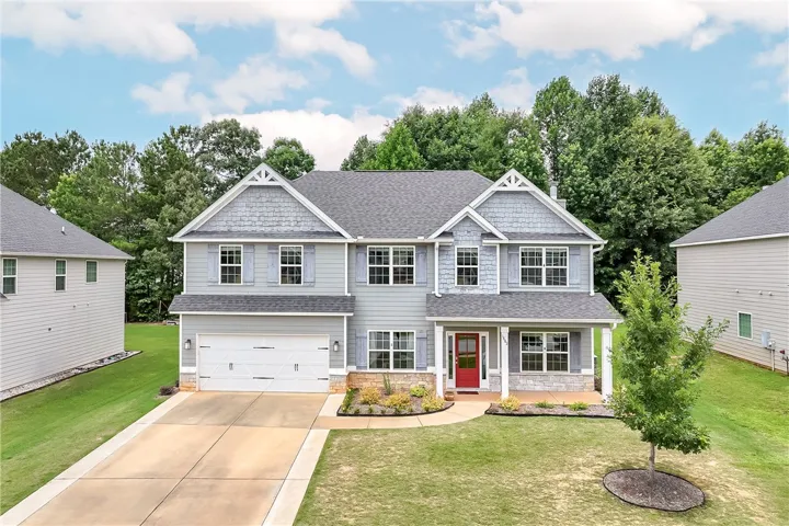 A welcoming front porch with a vibrant red door enhances this charming gray residence.