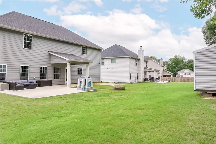 A spacious backyard features a covered patio, perfect for outdoor entertaining, alongside a well-maintained lawn and a quaint shed.
