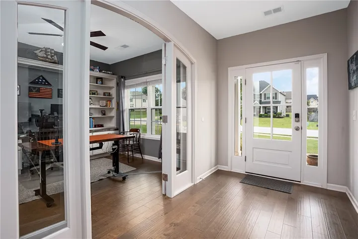 A welcoming entry offers rich wood flooring and a direct view into a versatile home office.