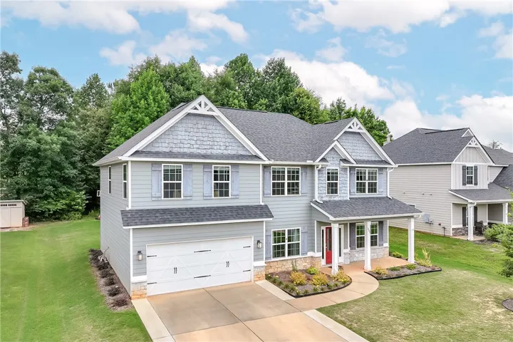 A handsome residence features a blend of siding styles, a practical driveway, and tasteful landscaping.