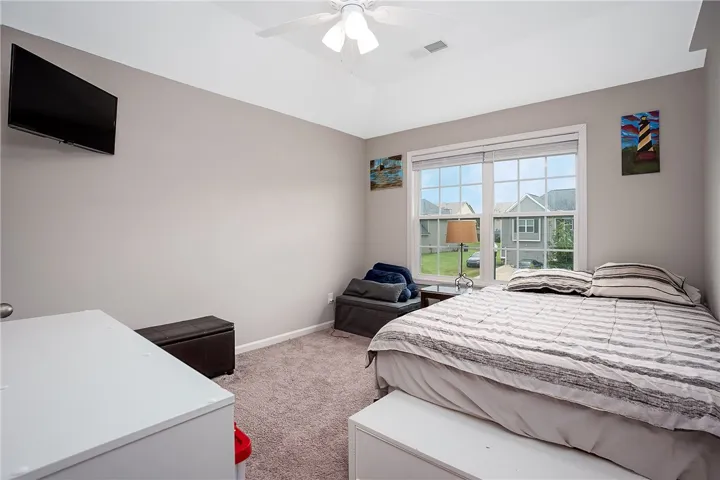 A comforting bedroom with soaring vaulted ceilings and a broad window offers a neighborhood vista.