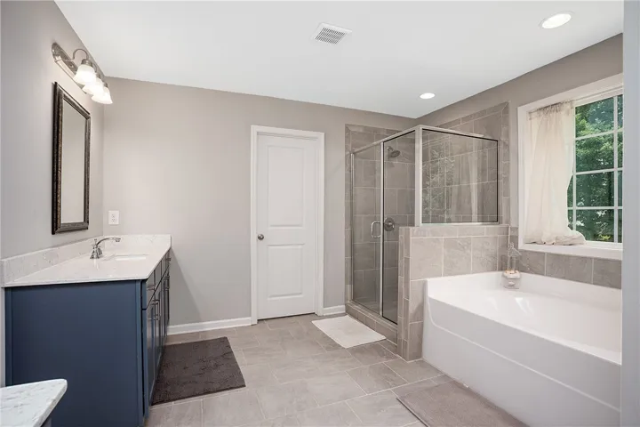 Luxurious bathing quarters feature a tiled shower and an inviting, spacious tub.