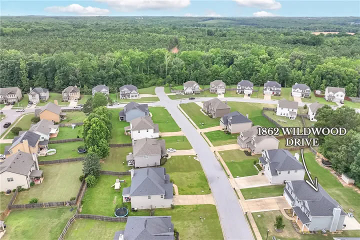 An aerial perspective reveals a vibrant neighborhood nestled among verdant woodland with paved streets and manicured lawns.