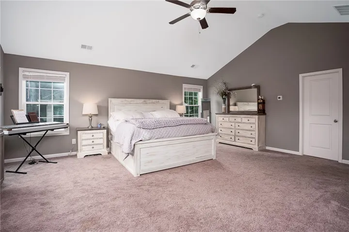 Sloped ceilings and a ceiling fan enhance the spacious feel of this well-lit primary bedroom.