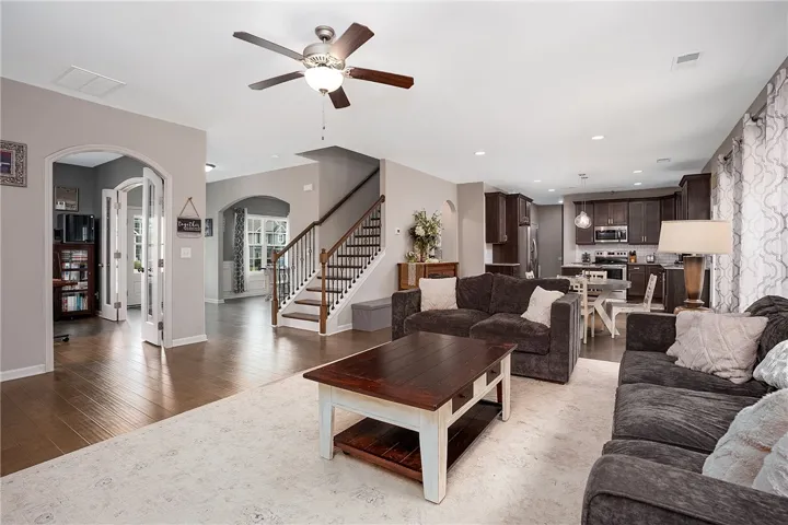 An inviting open-concept living area boasts lustrous hardwood flooring and convenient access to the kitchen and an adjacent office space.