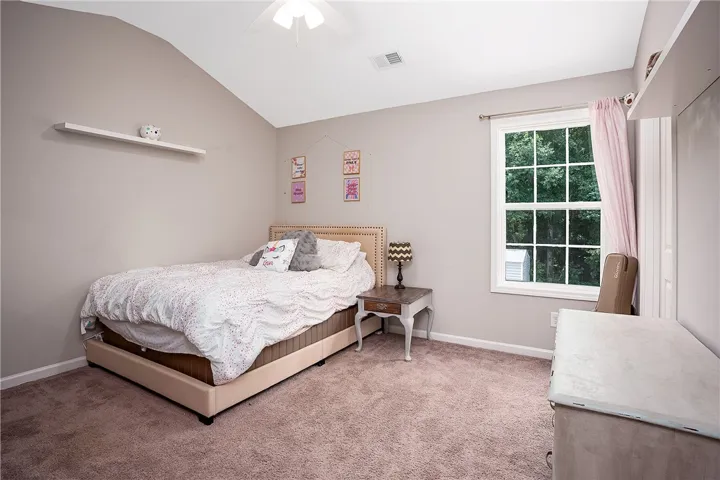 A cozy bedroom with a window overlooking green trees.