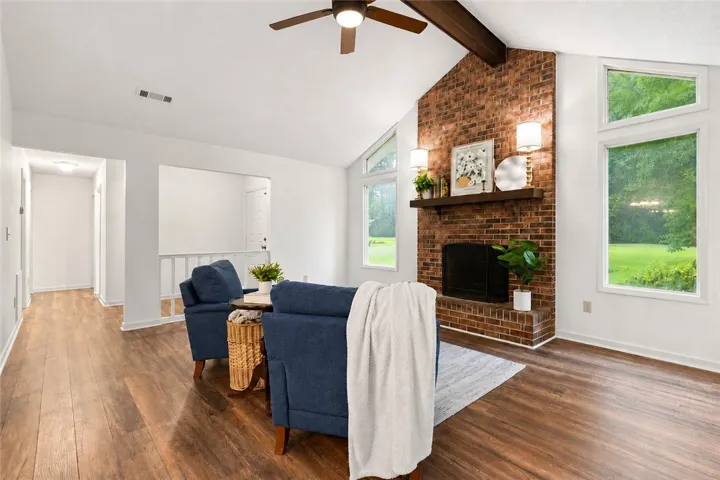 A striking brick fireplace grounds this comfortable living room with rich LVP flooring and a vaulted ceiling.  Guest bedrooms & laundry down hall.
