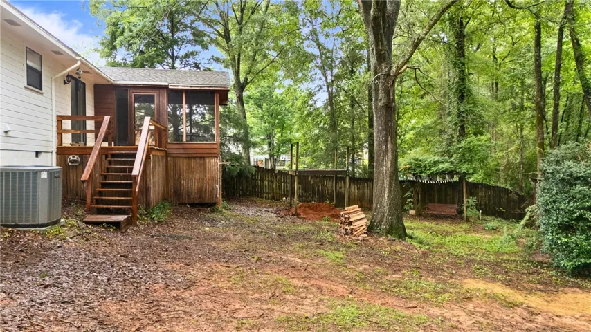 A spacious backyard with gentle slope, mature trees, storage and ample space for outdoor activities.