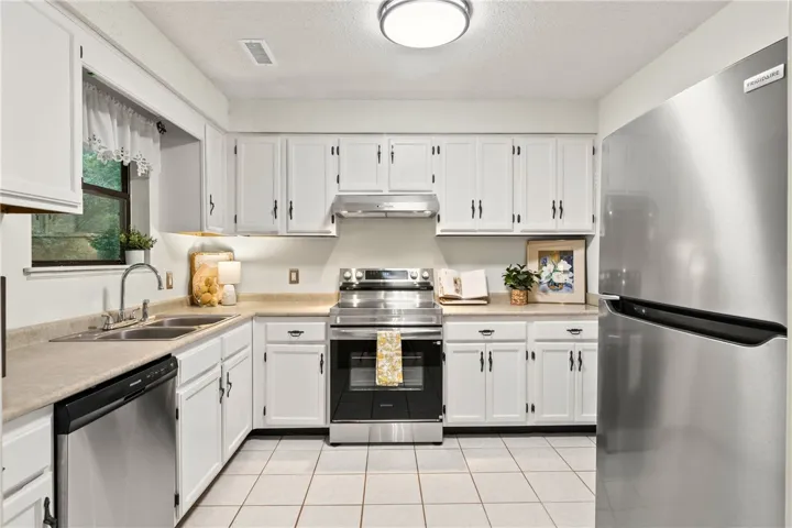 A well-equipped kitchen features white cabinetry, stainless steel appliances, and tile flooring.