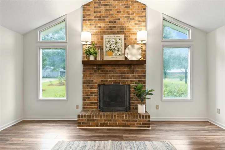Warm brick fireplace serves as a focal point, complemented by tall windows that invite abundant natural light into the space.