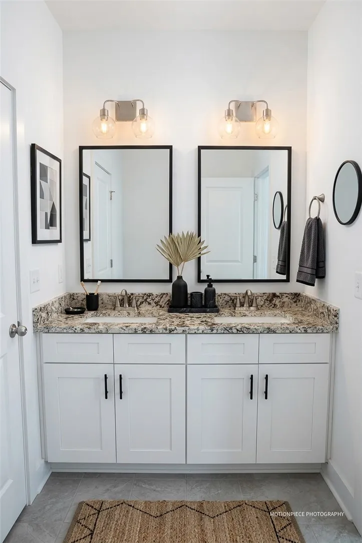 Double vanity with stone counters and dual mirrors offers practical elegance in this well-appointed bath.
