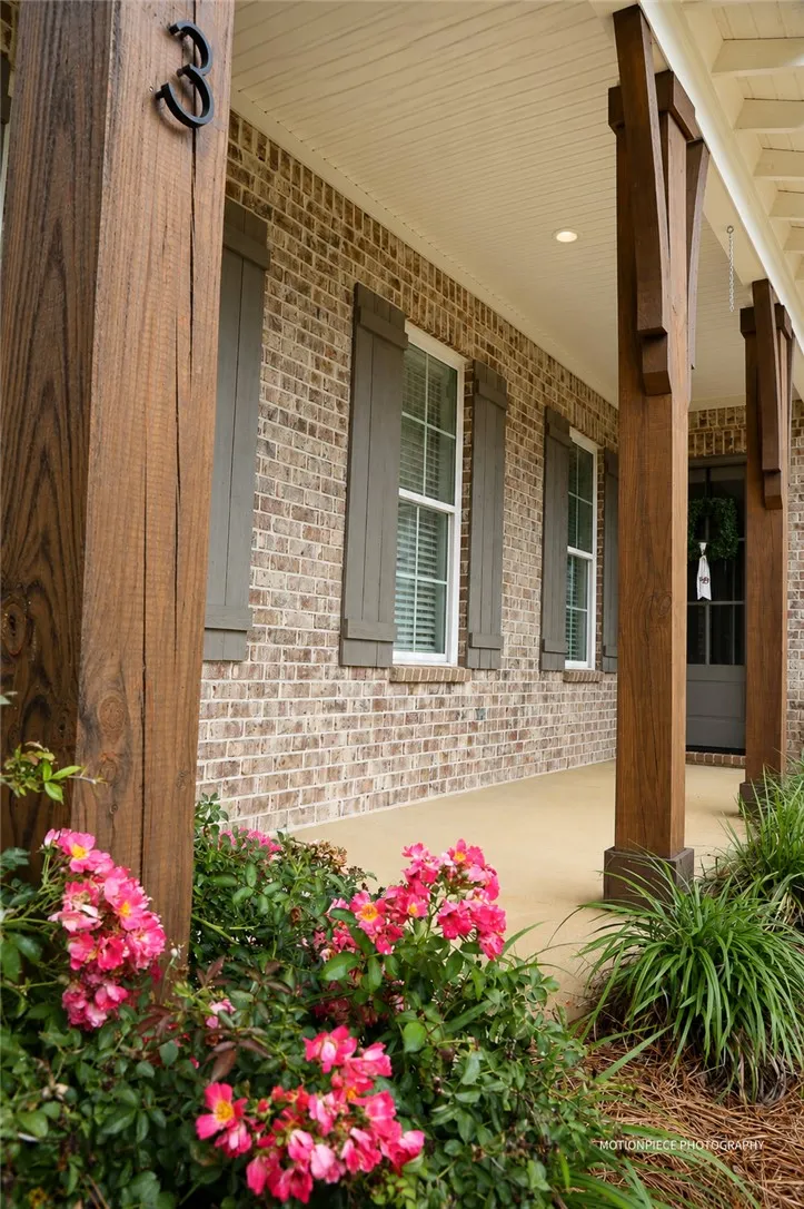 A welcoming front porch features sturdy wooden columns and vibrant floral landscaping.