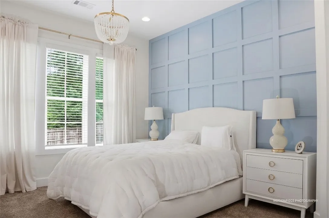 Elegant ceiling fixture and soft natural light illuminate this calming, thoughtfully designed bedroom.