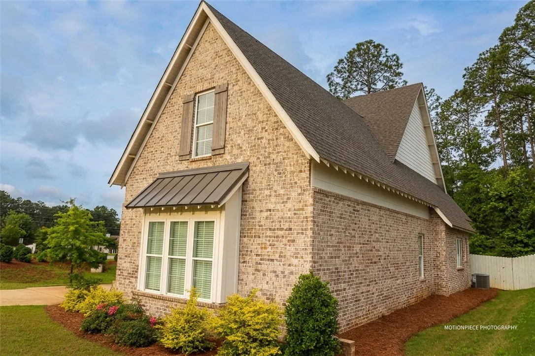 A classic brick exterior showcases a bay window with a metal awning, offering timeless curb appeal.