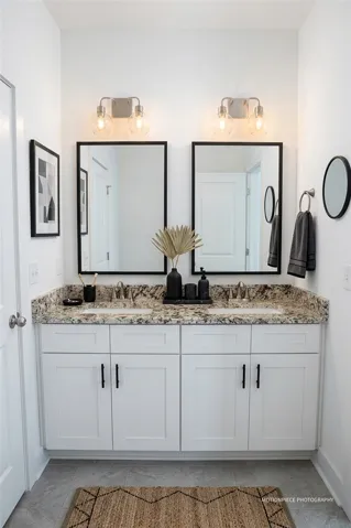 Double vanity with stone counters and dual mirrors offers practical elegance in this well-appointed bath.
