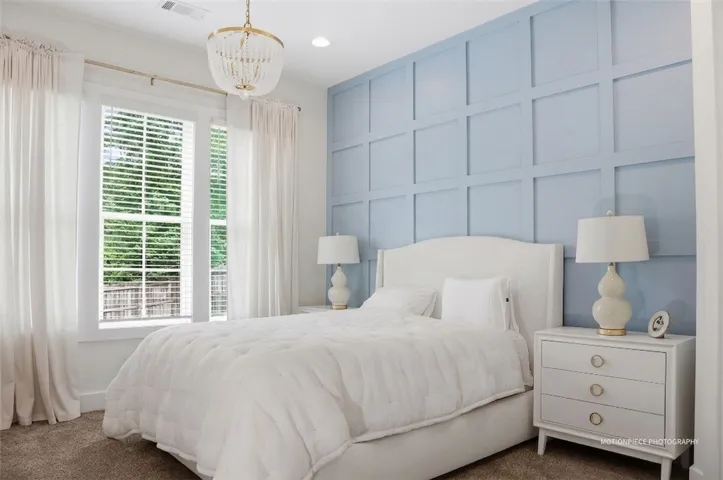 Elegant ceiling fixture and soft natural light illuminate this calming, thoughtfully designed bedroom.