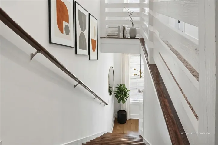 Hardwood stairs with a crisp white railing lead to a bright lower landing.