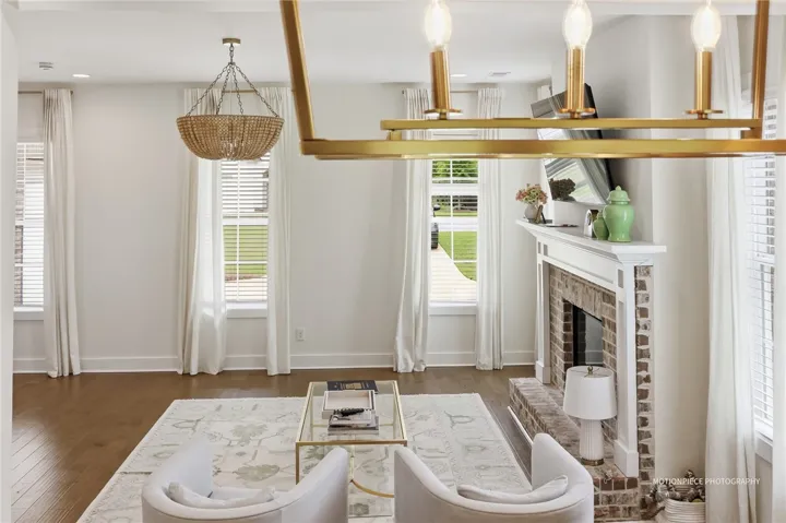 A refined living space showcasing a brick fireplace, hardwood floors, and elegant chandeliers.