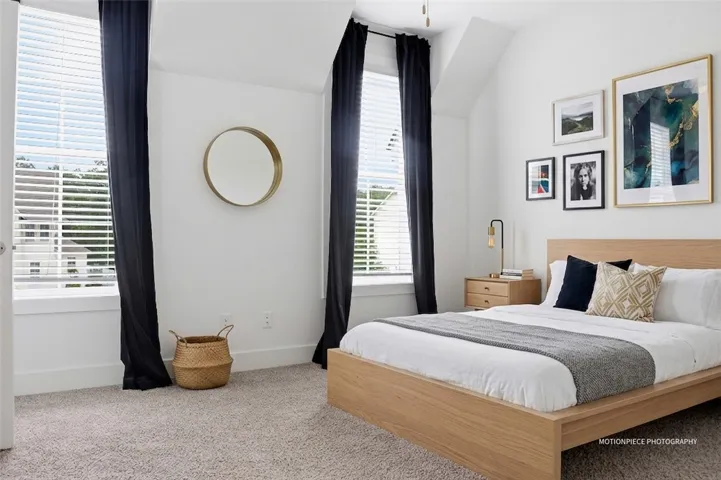 Well-lit sleeping quarters with plush carpeted flooring, featuring tall windows with privacy blinds.