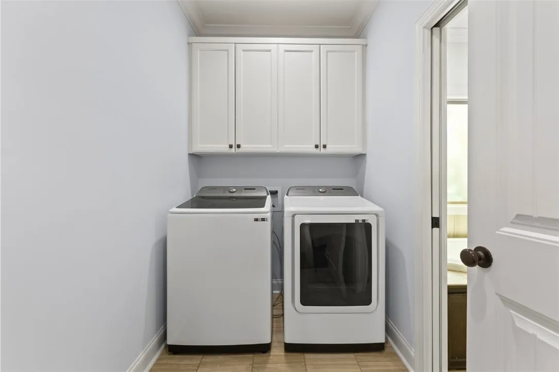 Functional laundry space featuring modern appliances and convenient overhead cabinetry.