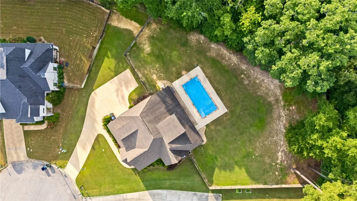 An aerial perspective showcases the inviting outdoor pool and verdant surroundings of this residential property.