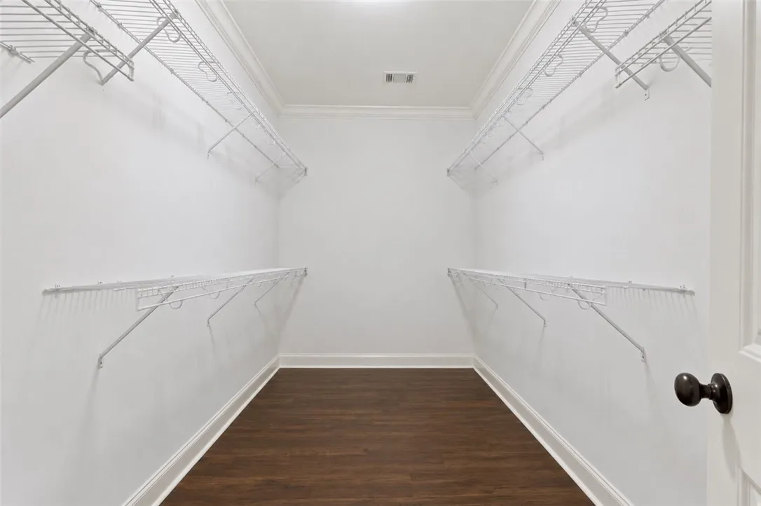 Walk-in closet offering ample storage with durable wire shelving and dark wood-look flooring.