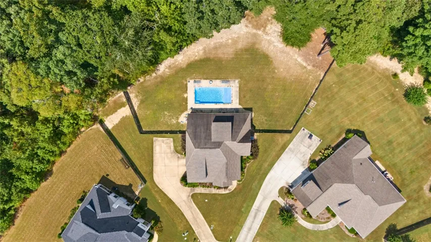 An aerial perspective reveals a serene residence with a private swimming oasis, nestled amongst verdant trees.
