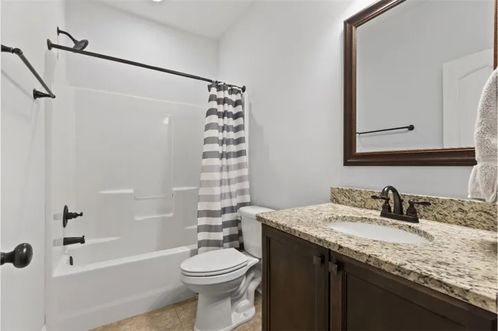 Refined bathroom with a broad granite-topped vanity and a pristine tub-shower combination.
